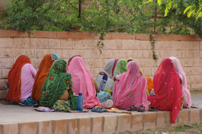 Mulheres sentadas na calçada com vestimenta típica indiana, Imagem